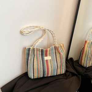 Détails d'un sac cabas tissé multicolore avec écusson en cuir et poignées blanches