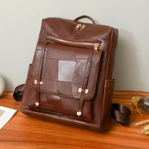 Chic dark brown patchwork leather backpack with gold zippers on a wooden table