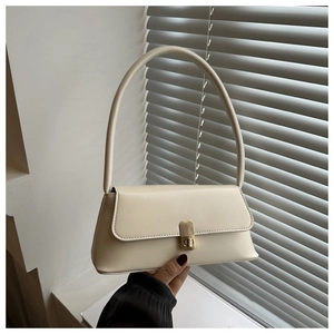 Detail of cream baguette bag featuring a sleek gold push-lock and smooth leather finish