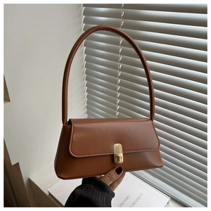 Detail of vintage caramel baguette bag featuring golden rectangular metal twist lock