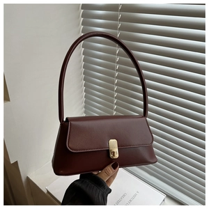 Detail of burgundy leather baguette bag featuring elegant gold clasp and sleek handle