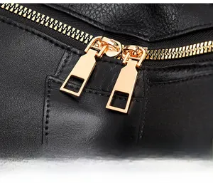 Détail de fermetures éclair en métal doré sur sac à dos en cuir noir texturé
