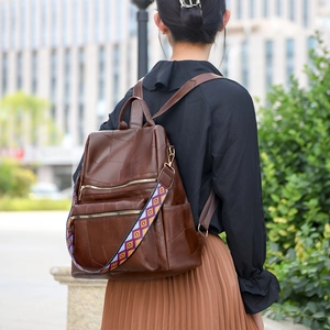 Women's vintage brown leather backpack with colorful geometric strap shown on a model