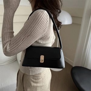 Classic black baguette shoulder bag with gold metal buckle shown on a model