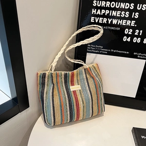 Détail du sac cabas tissé à rayures colorées avec poignée blanche et écusson en cuir