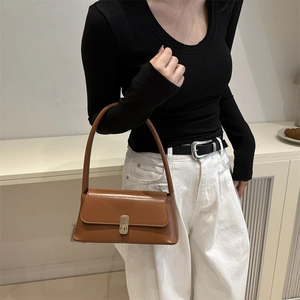 Retro brown baguette shoulder bag with metal buckle shown on a model in close-up shot