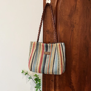 Sac fourre-tout tissé arc-en-ciel avec lanières brunes et étiquette de mode sur une porte