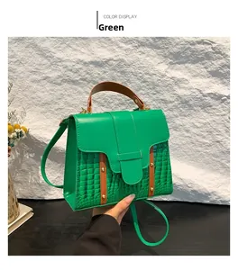 Detail of green crocodile texture handbag with brown leather strap and gold hardware