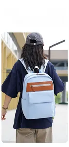 Outdoor shot of a light blue Oxford backpack with leather details shown on a model