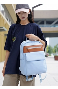 Detailed view of light blue backpack with brown leather accents for casual daily commuting