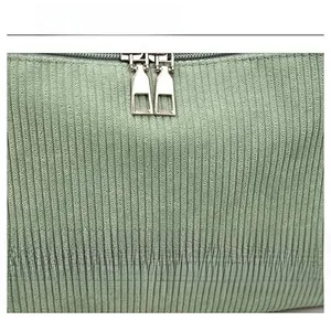 Detail view of double metal zippers and brown leather patch on green corduroy fabric