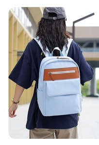 Close-up of a light blue casual backpack with leather trim on a city street
