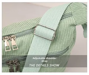 Detail view of adjustable wide shoulder strap and zippers on corduroy crossbody bag