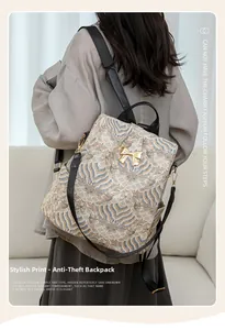 Detail of cream backpack with blue wave print, gold bow clasp, and anti-theft design