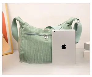 Size comparison of light green corduroy crossbody bag next to an iPad device
