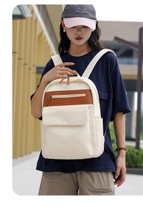 Detail of stylish cream oxford backpack with brown leather accents on a model outdoors