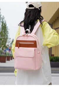Pink nylon backpack for school with brown faux leather contrast stripe outdoor scene