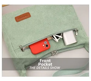 Detail of light green corduroy bag showing a zippered front pocket for phone and essentials