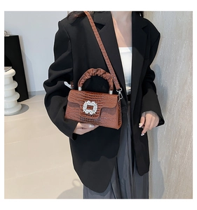 Detailed texture of brown crocodile-embossed leather bag with silver rhinestone buckle