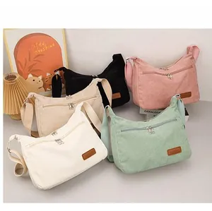 Detail of five corduroy crossbody bags in various pastel colors with leather labels