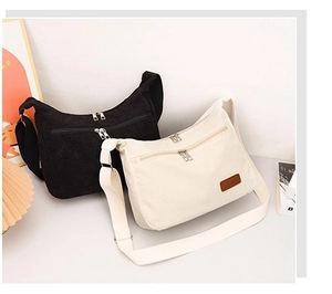 Detail of corduroy crossbody bags in black and beige with adjustable straps and zipper pockets