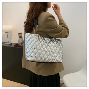 Detail of silver quilted tote bag featuring metallic finish and gold chain strap accents
