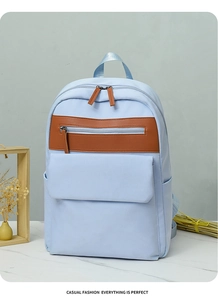 Detail of light blue waterproof backpack with brown leather accents and multi-pocket layout