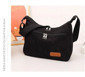 Detail of black corduroy shoulder bag showing dual zipper pockets and fashion leather patch