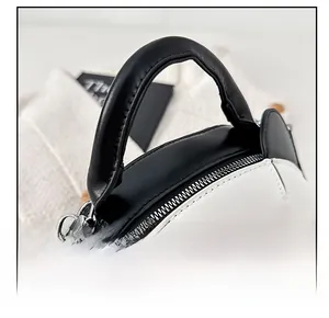 Détail du sac panda avec des poignées noires rondes et une fermeture éclair en métal argenté