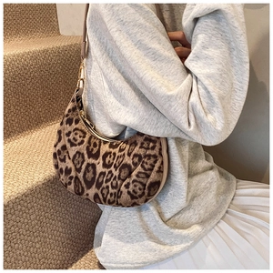 Detail of leopard print crescent bag with golden zipper on model in natural light