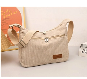 Detail of cream corduroy crossbody bag featuring dual zippers and adjustable canvas strap