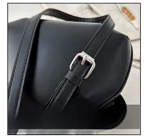 Détail de la bandoulière réglable en cuir noir avec boucle ardillon en métal argenté