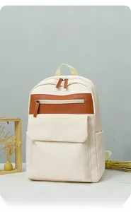 Detail view of cream oxford backpack with brown leather accent in a minimalist indoor setting