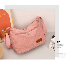 Detail of pink corduroy shoulder bag showing double zipper pockets and brown leather tag