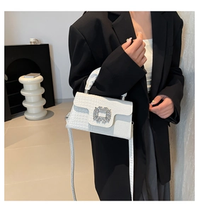 Detail of white crocodile-embossed handbag with square crystal buckle and long strap