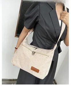 Detailed close-up of corduroy crossbody bag texture and leather fashion label detail