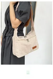 Detail of beige corduroy crossbody bag featuring dual zippers and wide fabric strap