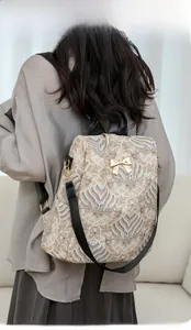Detailed view of vintage patterned backpack with golden bow and leather straps on model