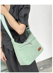 Detail of light green corduroy crossbody bag with adjustable wide strap and fashion patch