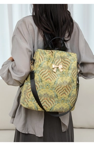 Back view of woman wearing yellow brocade backpack with traditional cloud patterns