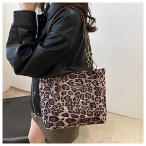 Detail of leopard print tote bag with brown straps and elegant gold metal chain hardware