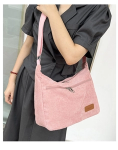 Detail view of pink corduroy crossbody bag with adjustable strap and leather logo patch