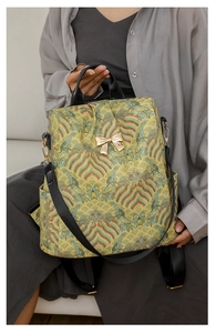 Detail of yellow vintage floral backpack with golden bow and side pocket on a model