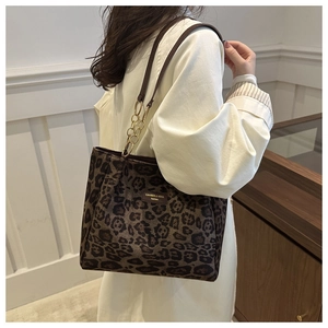 Leopard print tote bag with brown leather straps and gold chain detail on model