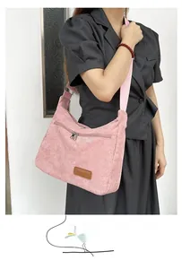 Detail of pink corduroy crossbody bag featuring a brown leather Fashion label and wide strap