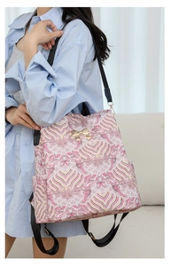 Detail view of pink and yellow wave print backpack with gold bow buckle on model