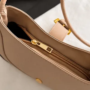 Gros plan sur la fermeture éclair en métal doré et les coutures de ce sac beige chic
