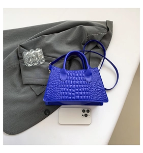 Royal blue crocodile pattern handbag shown with smartphone for size comparison