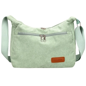 Detail of light green corduroy bag showing metal zipper and brown leather label