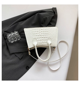 Top view of white croco-embossed tote bag styled on a gray blazer with gold hardware